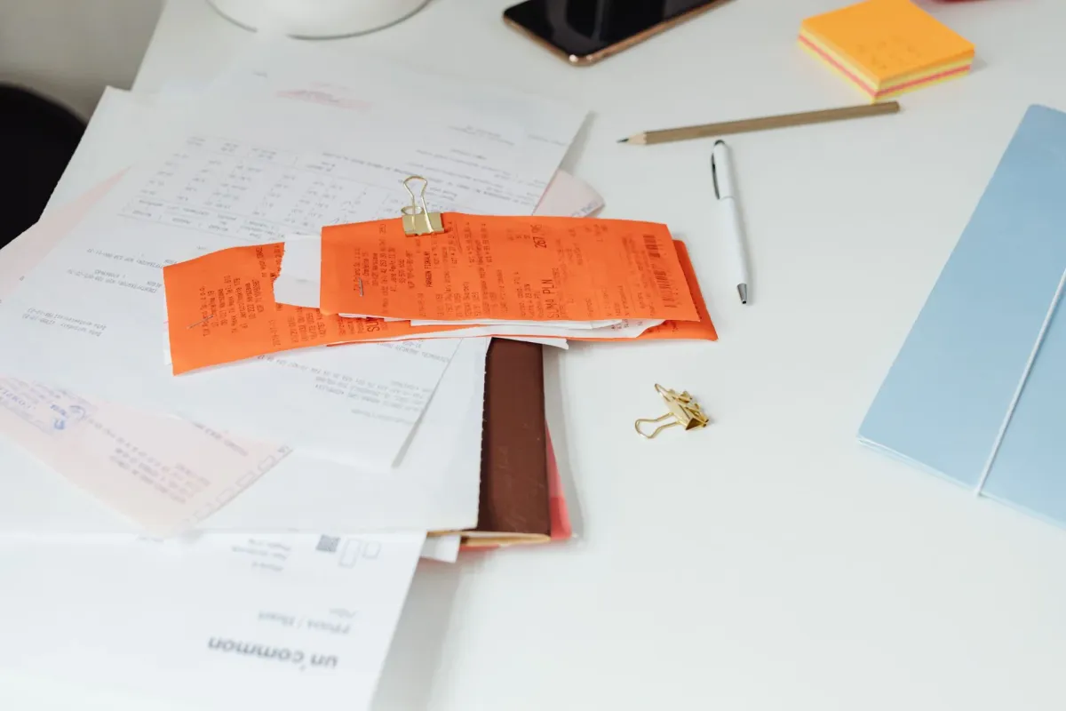 Receipts, documents, and office stationery arranged on a tidy desk.