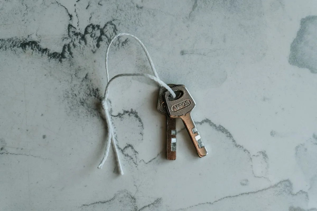Two metal keys tied together on a string against a marbled background.