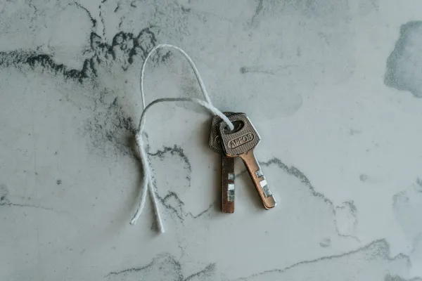 Two metal keys tied together on a string against a marbled background.