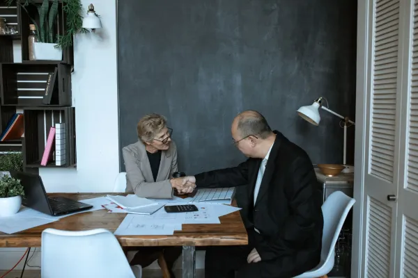 A handshake across a desk in a modern office.
