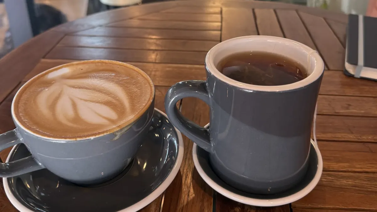 A latte and a mug of tea on a wooden table inside a Harrisonburg coffee shop