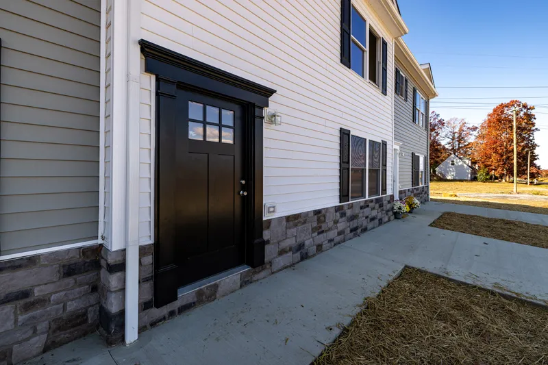 Front entry detail at twilight showing dark stained craftsman door and stone-veneer base