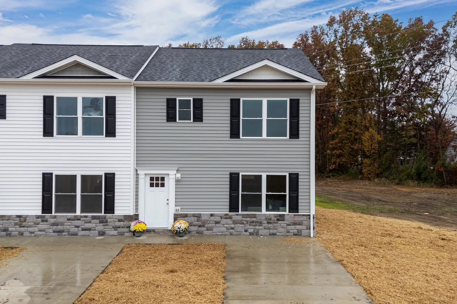 A Forest Station townhome end-unit exterior with gray vinyl siding, black shutters, and stone-veneer water table