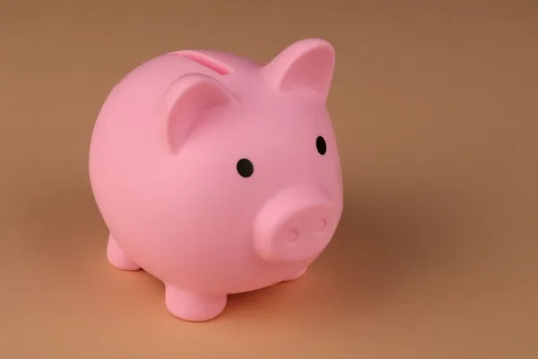A pink piggy bank on a plain brown backdrop.