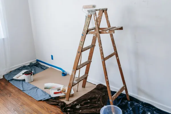 A room under renovation with a wooden ladder and paint supplies.