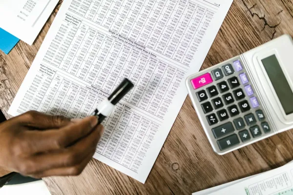 Financial documents and a calculator on a wooden table.