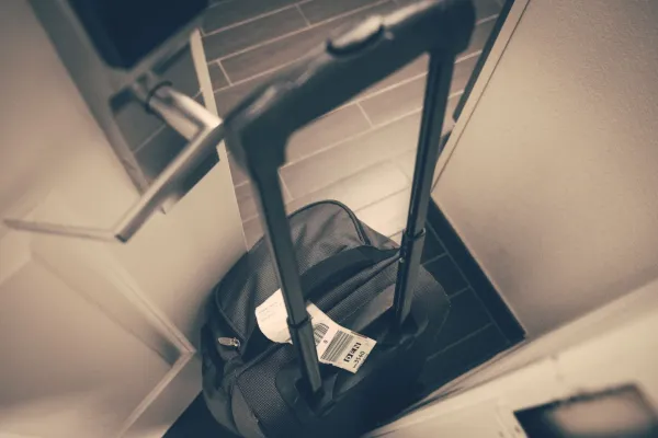 A travel suitcase with a tag beside a door.