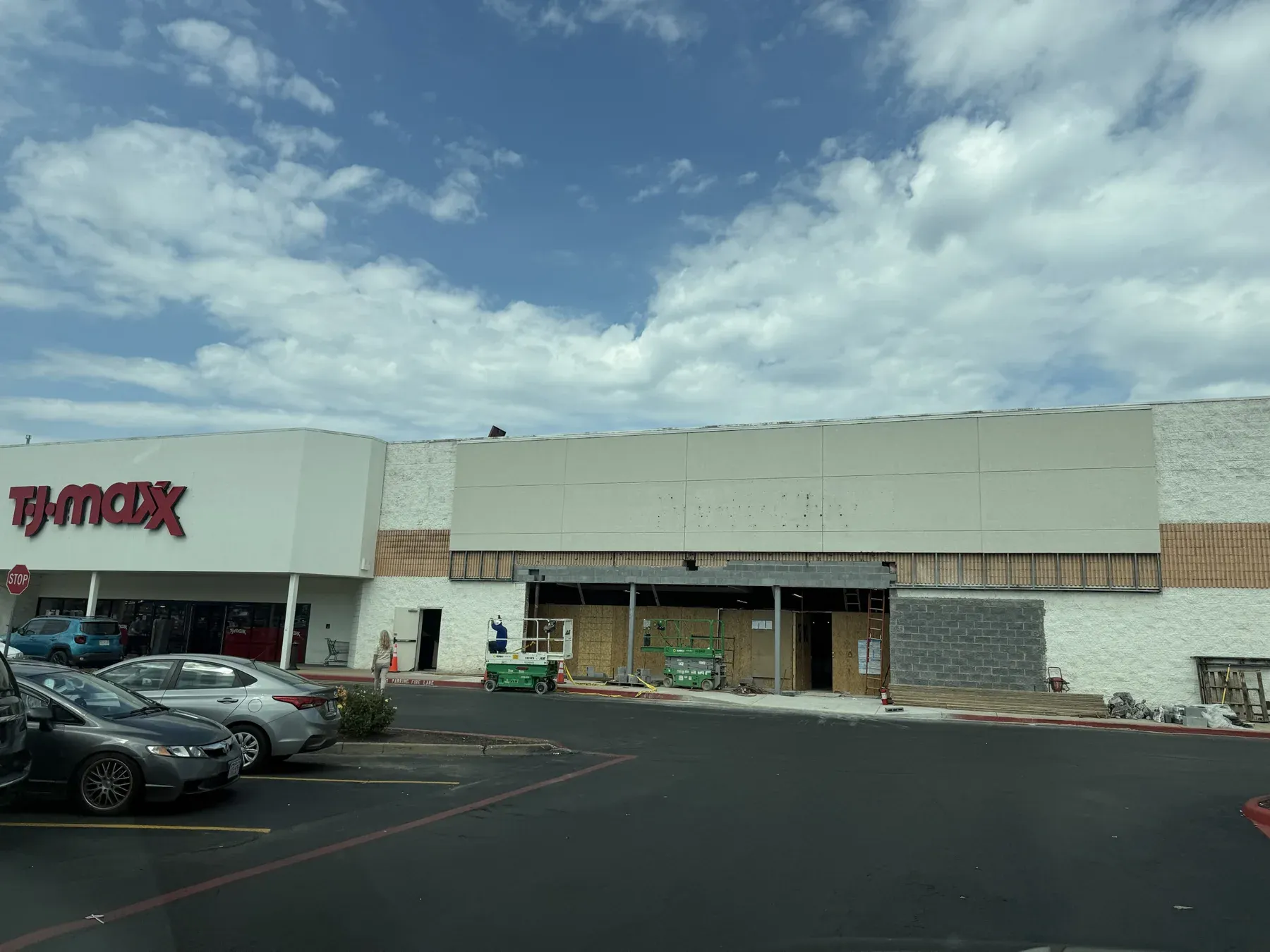 The former Party City bay next to TJ Maxx with its storefront removed, new concrete block walls under construction, and scissor lifts inside